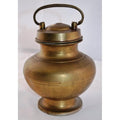 Close-up of antique brass milk jar with lid and handle, hand casted, set against plain white background.