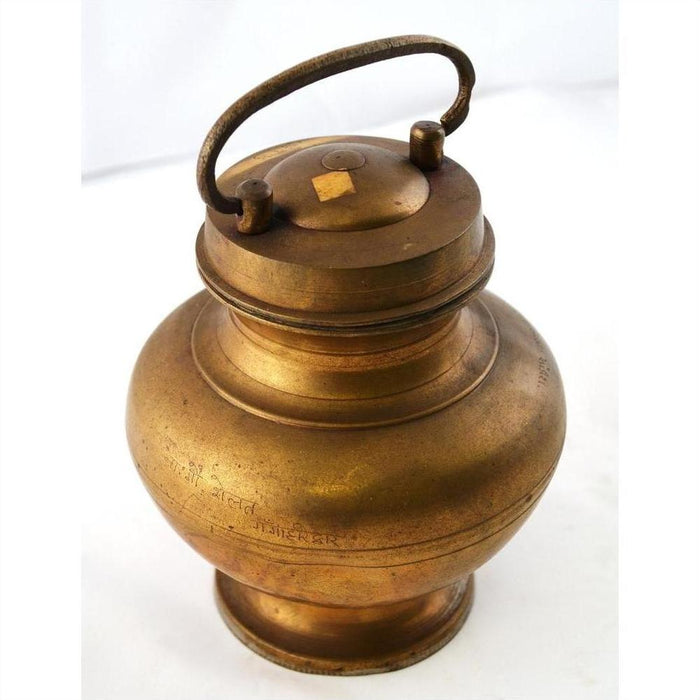 Close-up of antique brass milk jar with handle and lid, hand casted in traditional Indian style.