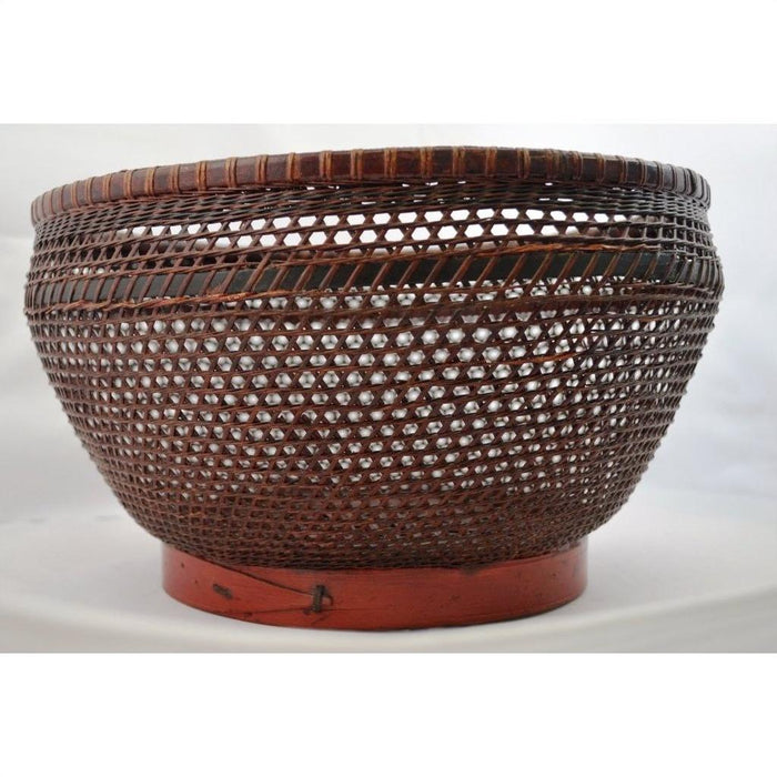 Brown woven rattan storage basket with round shape, red base, and open lattice-style sides, close-up view.