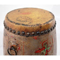 Close-up of faded, hand-painted wood and leather drum with metal studs and floral pattern.