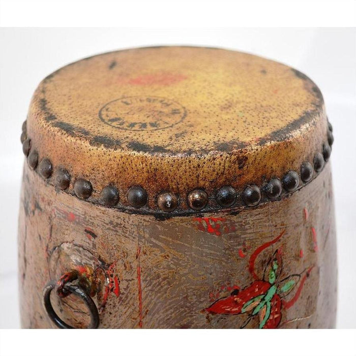 Close-up of faded, hand-painted wood and leather drum with metal studs and floral pattern.