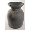 Close-up of a large, dark, round antique Indian metal milk storage container with ridged horizontal lines and wide neck.
