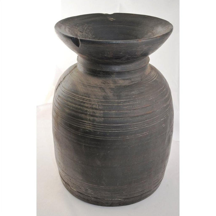 Close-up of a large, dark, round antique Indian metal milk storage container with ridged horizontal lines and wide neck.