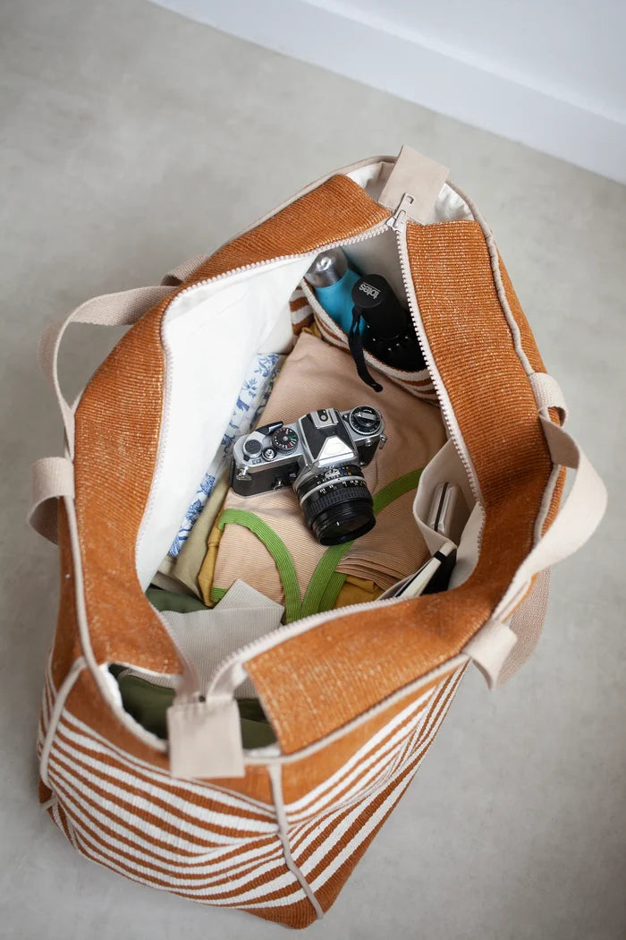 Brown and beige striped bag  made using the Away Tote PDF Sewing Pattern with camera and items on a light gray floor.