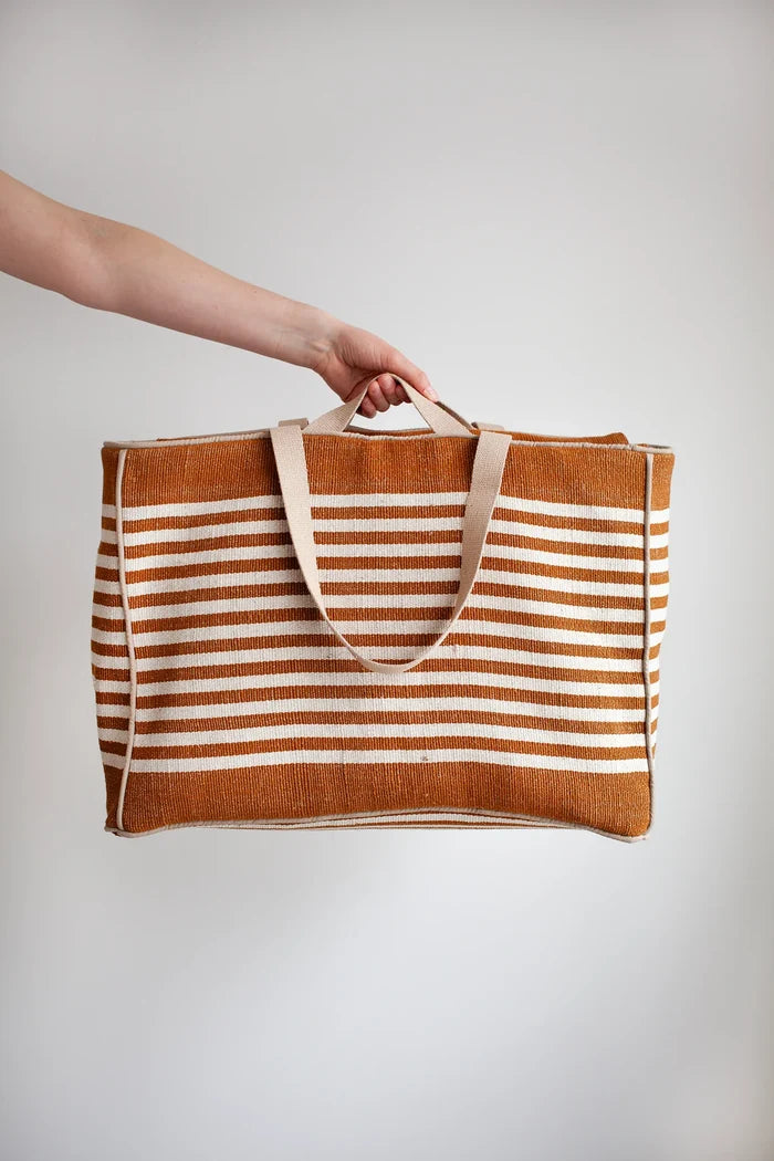Striped tote bag with a hand made using the Away Tote PDF Sewing Pattern  holding it against a plain background