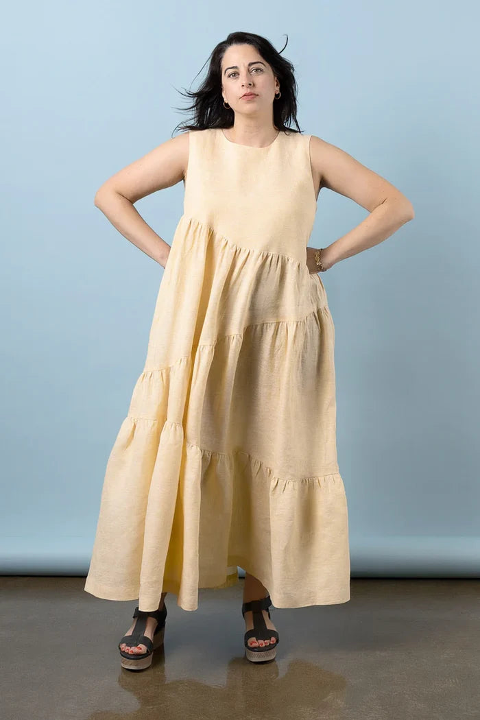 Woman wearing a beige sleeveless dress against a plain background