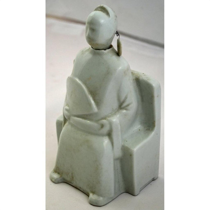 White porcelain Blanc de Chine doll, faceless, seated holding a fan, in traditional attire with earring.
