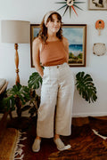 Lady wearing natural colour linen pants made of Bottlebrush Pants and Shorts Sewing Pattern - High-Waisted Flared Pants and Mini Shorts