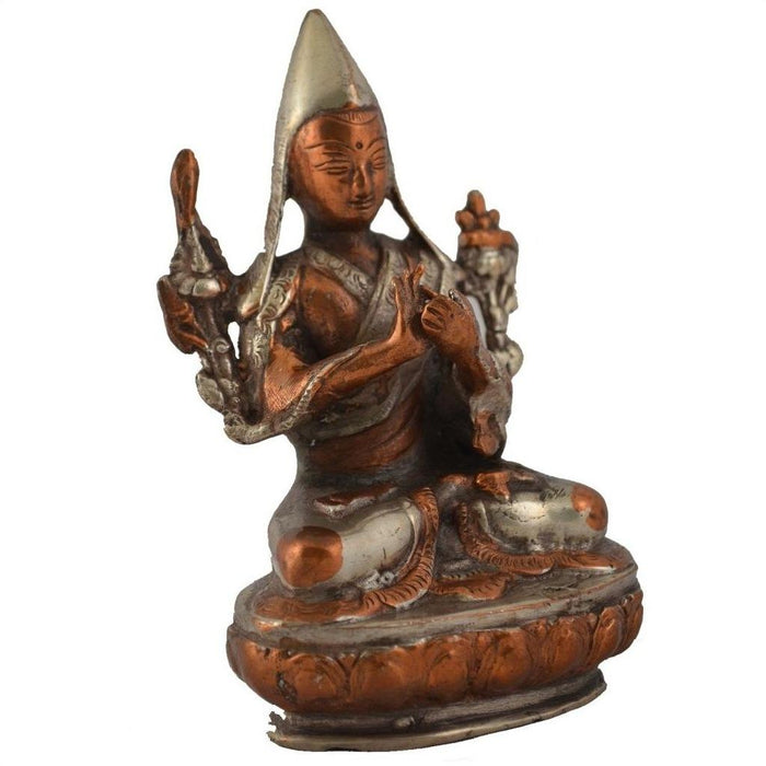 Brass deity statue in ornate robes and pointed hat, seated peacefully, brass details visible, close-up view.