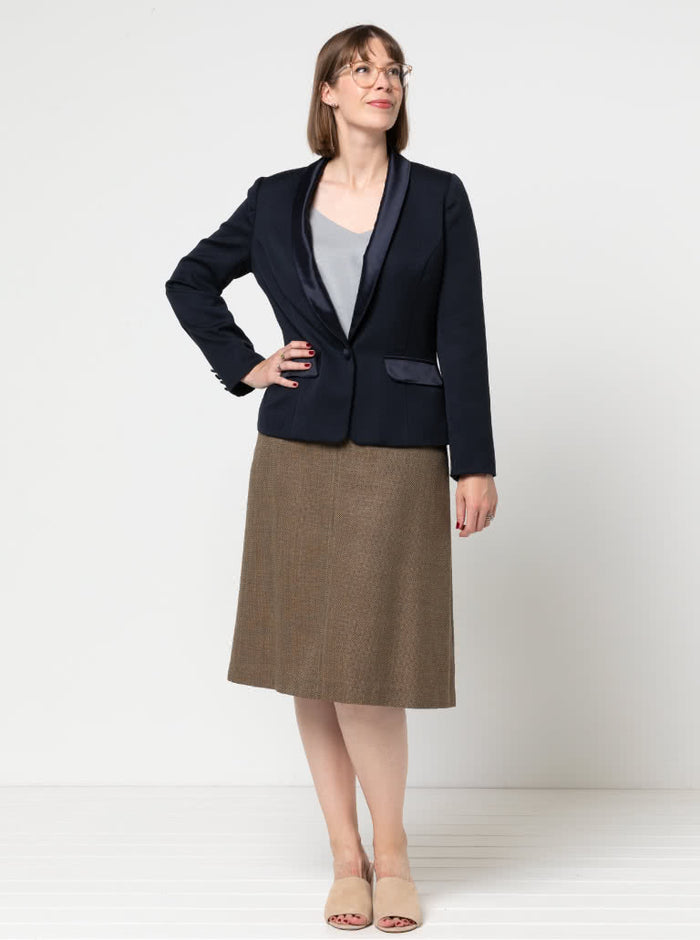 Woman wearing a navy  Jacket with contrast shawl collar and pocket flap made using the Bronnie Tuxedo Jacket Sewing pattern and brown skirt against a white background