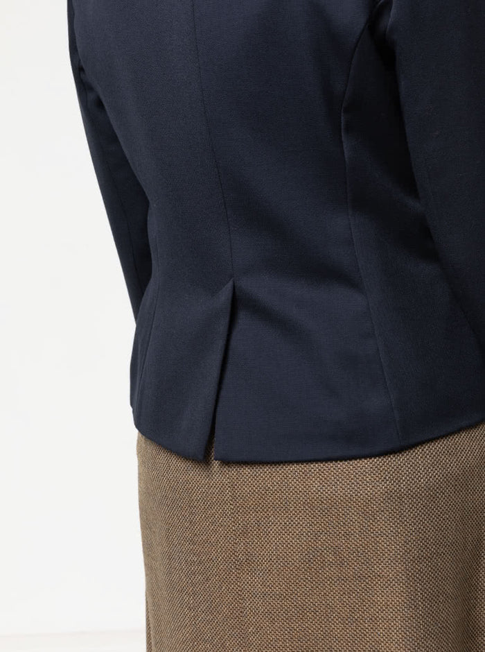Close-up of a navy blazer made using the Bronnie Tuxedo Jacket Sewing pattern  and brown skirt on a light gray background