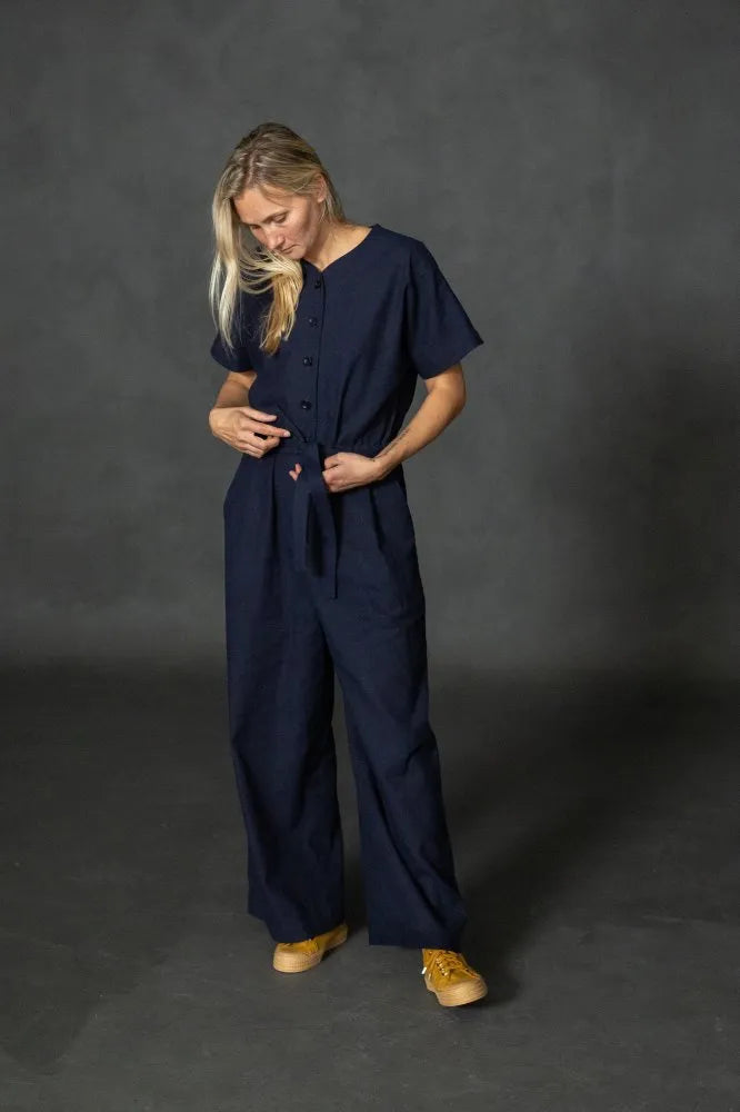 Person wearing a navy blue cassidy jumpsuit against a dark gray background