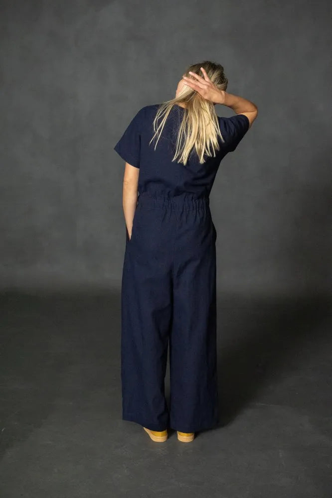 Person wearing a navy blue  cassidy jumpsuit against a dark gray background