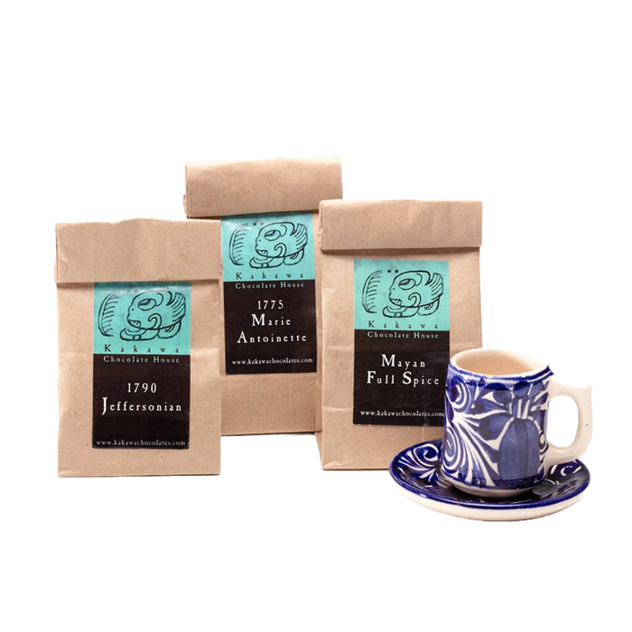 Three packaged chocolate drinking elixirs with labels representing different flavours, alongside a ceramic cup and saucer.