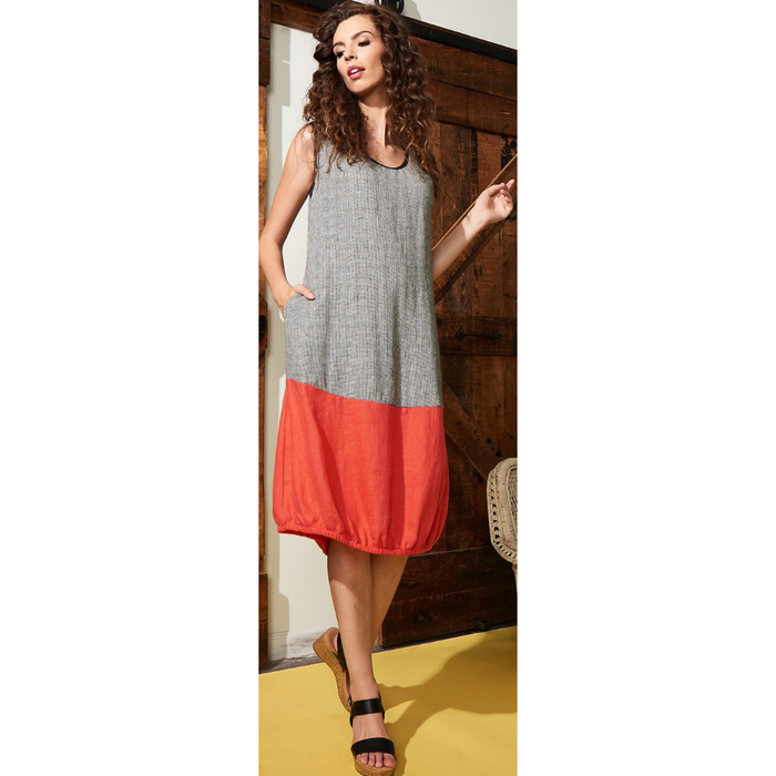 A woman wearing a mini houndstooth pattern dress with a bright orange elastic gathered hemline, standing in a room with wooden doors and a yellow floor.