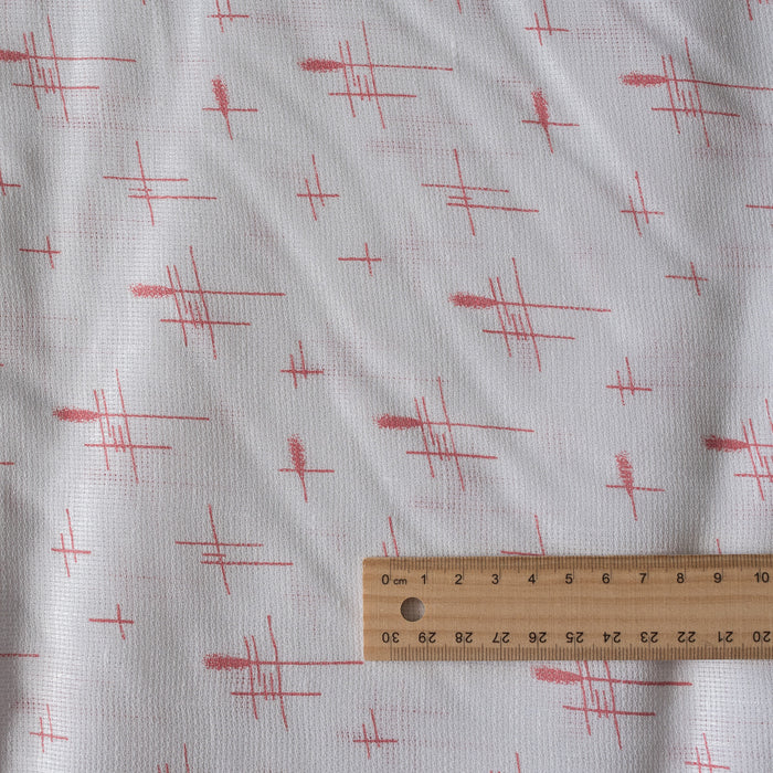 Sheer white 100% linen fabric with delicate red crosshatch print and a loose, elegant weave