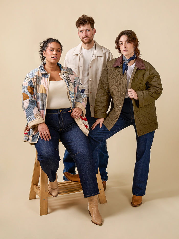 Three people wearing jackets and jeans against a beige background