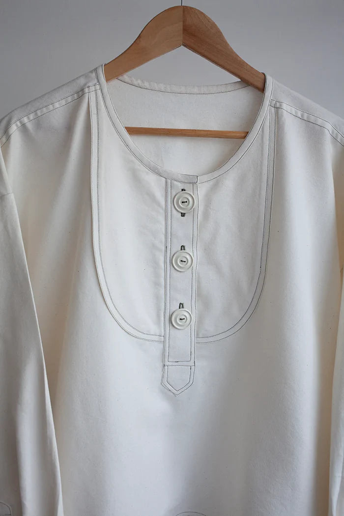 Customizable French Smock sewing pattern with options for button or zip fastening, various bib shapes, and optional trims, perfect for creating a unique garment.