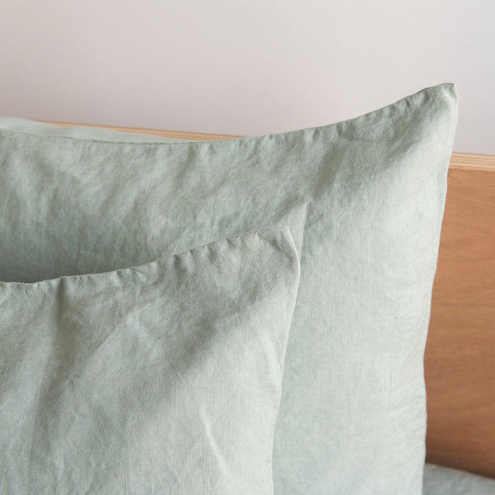 Harbour Sage European linen pillowcases  on a wooden headboard