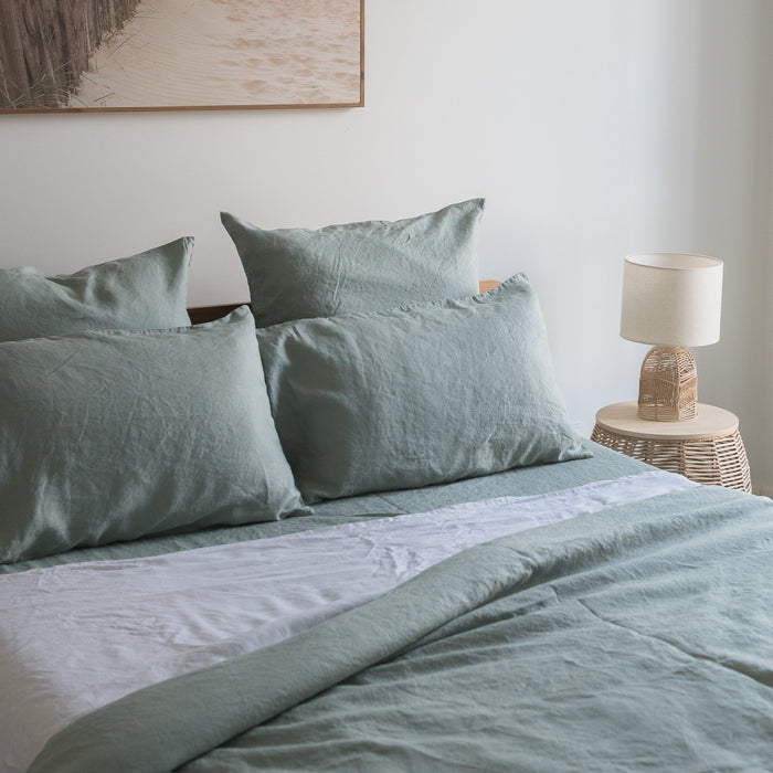Bed with Harbour Sage linen fitted sheet  and pillows in a bedroom setting.