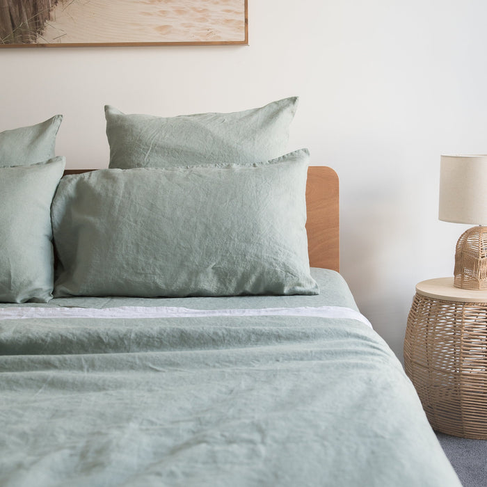 Bed with green bedding and Harbour Sage linen pillowcases  in a bedroom setting.