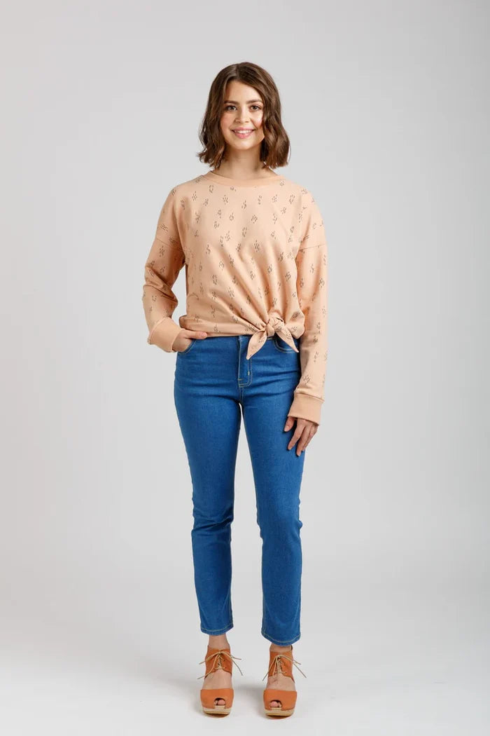 Woman wearing a beige Jarrah sweater and blue jeans on a white background