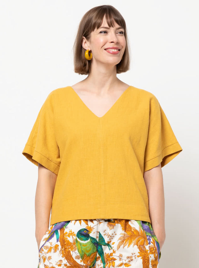 Joan Woven Top sewing pattern featuring a square shape, V-neck, extended shoulder line with band, and wide hem facings, suitable for washed linen, charmeuse, crepe, and rayon fabrics.