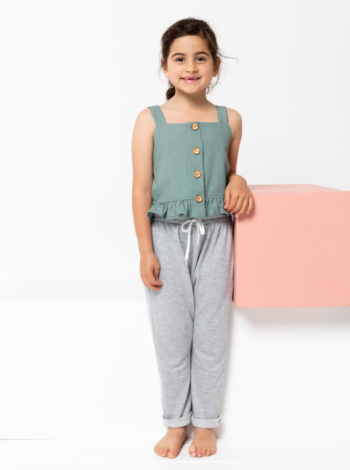 Kit Kids Tank Top sewing pattern, featuring a button-through top with frilled hem and adjustable shoulder straps for kids, suitable for linen, cotton, and denim fabrics.