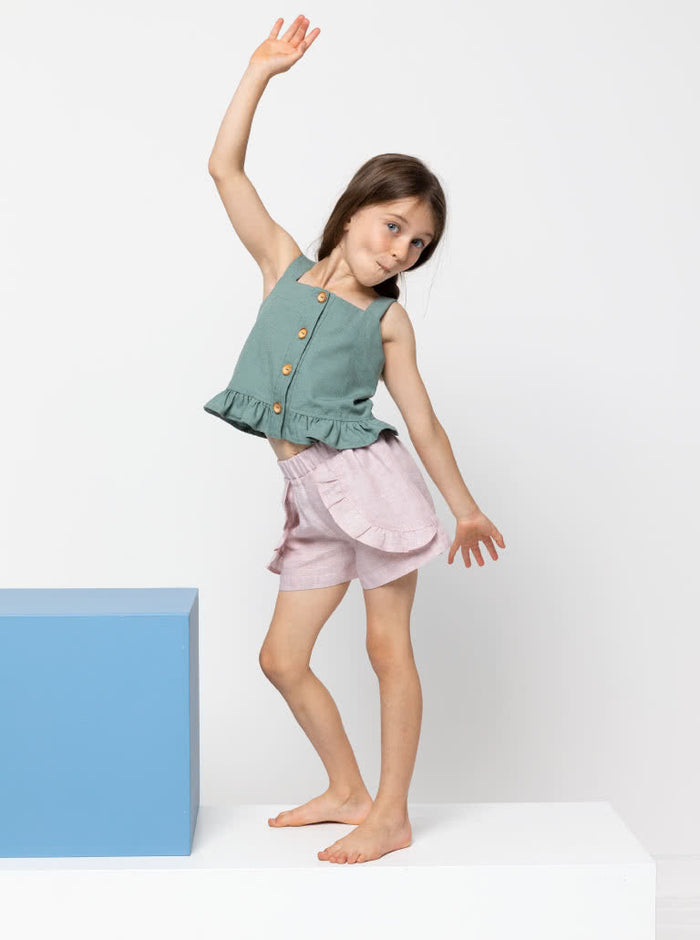 Kit Kids Tank Top sewing pattern, featuring a button-through top with frilled hem and adjustable shoulder straps for kids, suitable for linen, cotton, and denim fabrics.