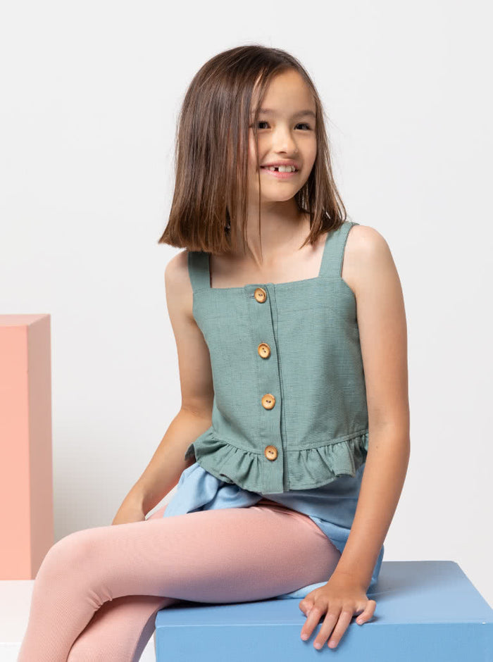 Kit Kids Tank Top sewing pattern, featuring a button-through top with frilled hem and adjustable shoulder straps for kids, suitable for linen, cotton, and denim fabrics.