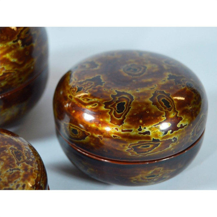 Yellow, gold, and dark brown lacquered jewelry boxes set with glossy marbled pattern, close-up view.