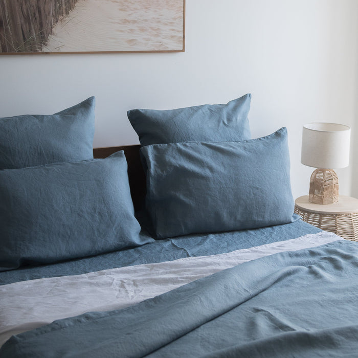 Lake Blue flat sheet 100% linen on a bed with a lamp and painting in the background