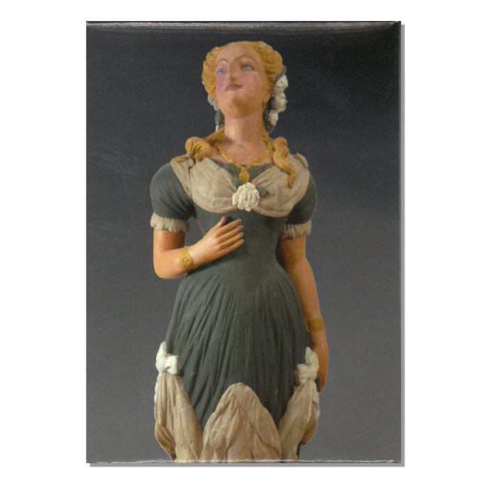 A magnet depicting a figurehead from the bark Marie, painted wood artwork of a woman in historical clothing.