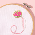 Embroidery hoop with pink thread and a floral embroidery design on a light pink background