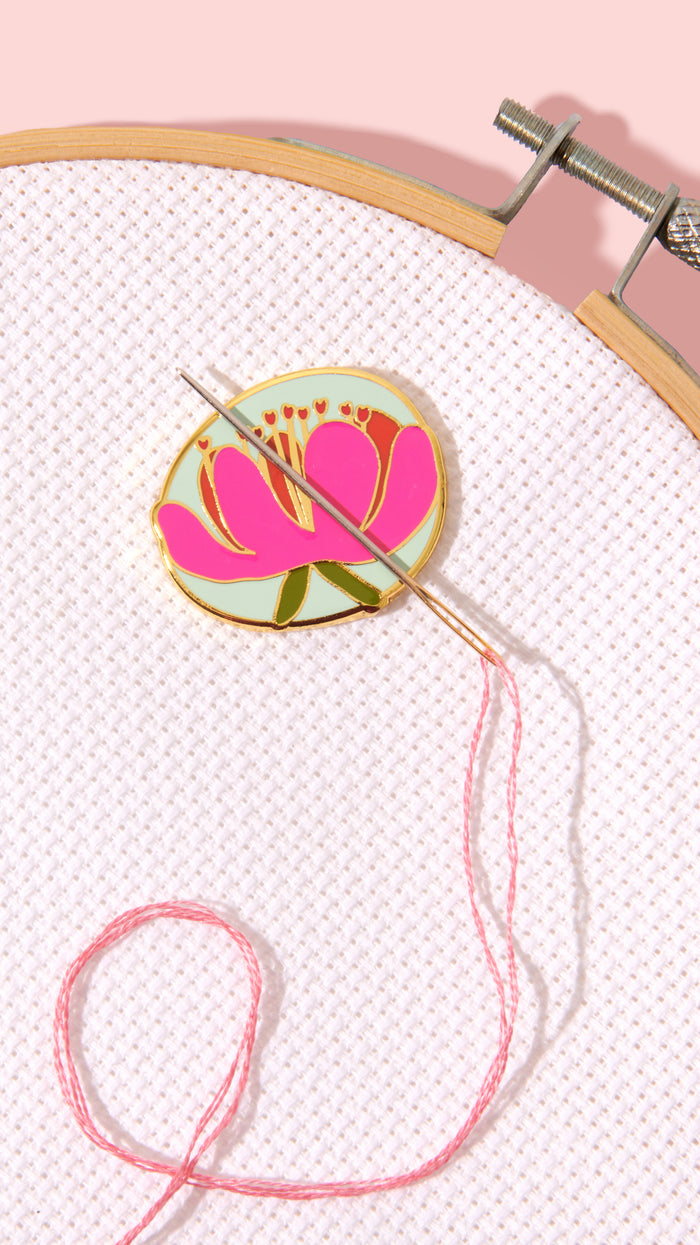 Embroidery hoop with floral design and pink thread on a light pink background