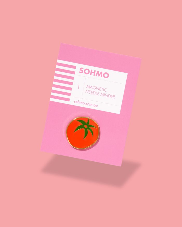 Pin with tomato design on pink card with 'SOHMO' branding against a pink background