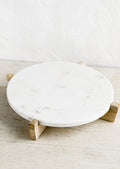 A round white marble riser on wooden X stand.