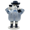 A ceramic figurine of a European-inspired character with a removable hat, dressed in blue and white striped attire, holding a cup.