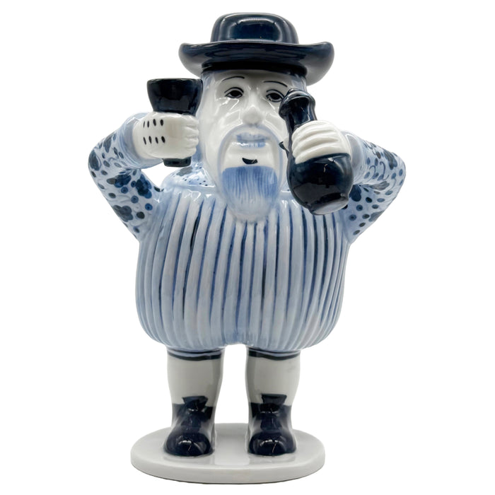 A ceramic figurine of a European-inspired character with a removable hat, dressed in blue and white striped attire, holding a cup.