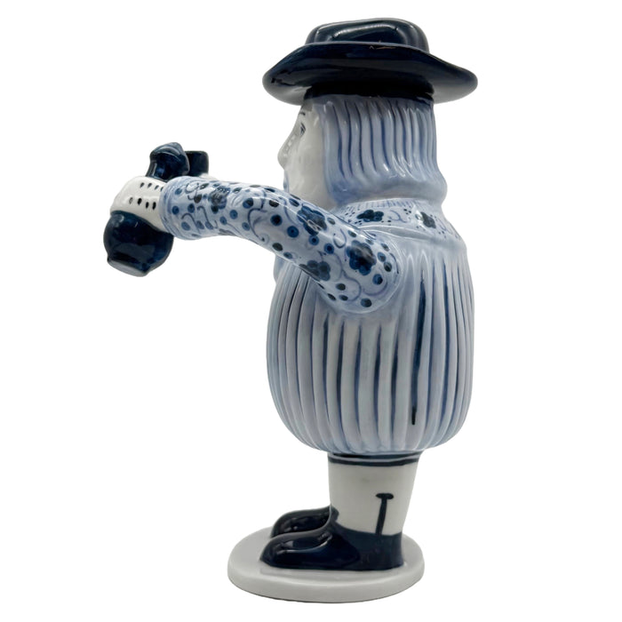 A ceramic figurine of a European-inspired character with a removable hat, dressed in blue and white striped attire, holding a cup.
