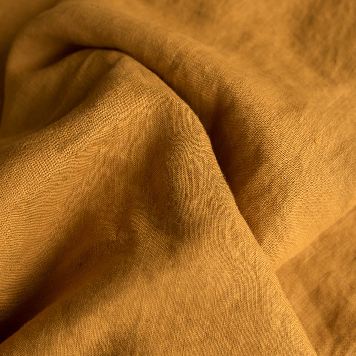 Close-up of Mustard extra wide 100% linen fabric with visible texture