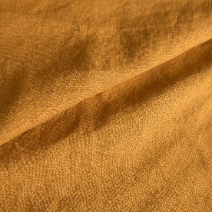 Close-up of Mustard extra wide 100% linen fabric with a textured pattern