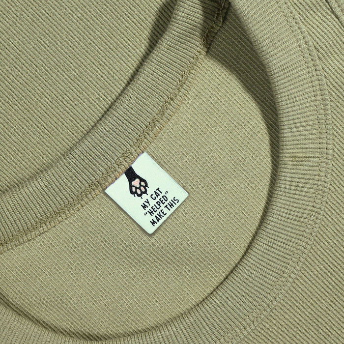 Close-up of a bgreen fabric with a label featuring a paw print design and text.