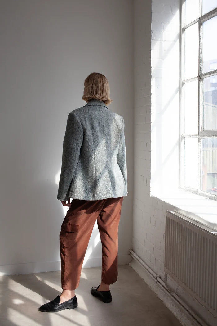 Person wearing a light blue jacket made using Naomi Blazer PDF Sewing Pattern  and brown pants standing in a room with a large window.