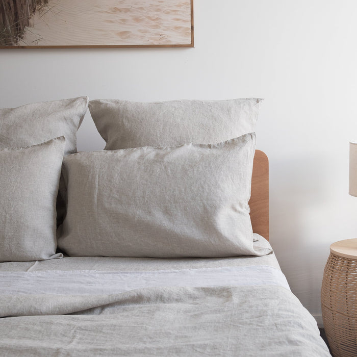 Neatly made bed with  Natural linen fitted sheet and pillows in a bedroom setting.