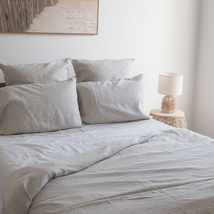 Neatly made bed with  Natural linen fitted sheet  and pillows in a bedroom setting.