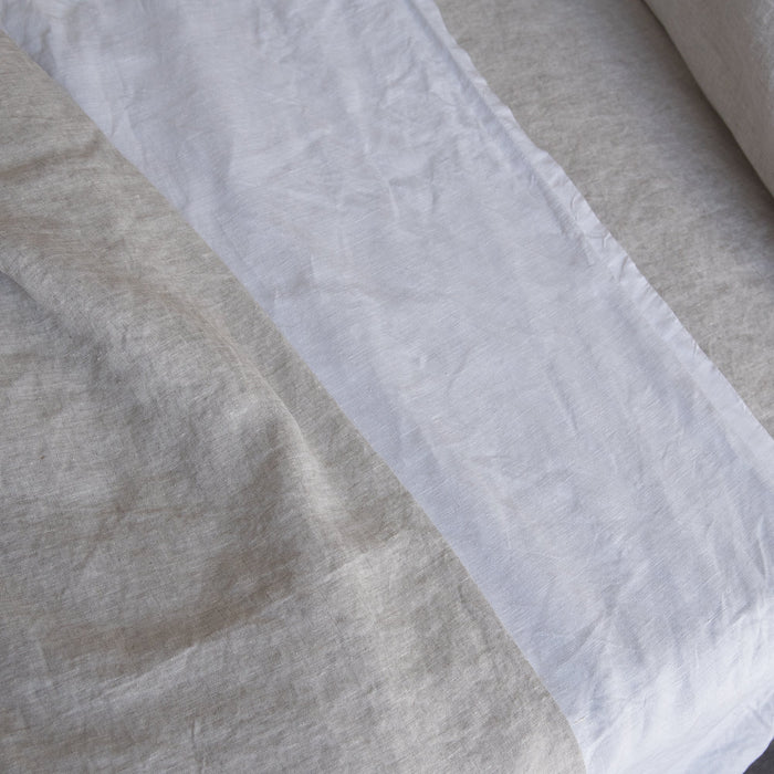 Close-up of Natural linen flat sheet soft beige bedding and white fabric with a textured pattern