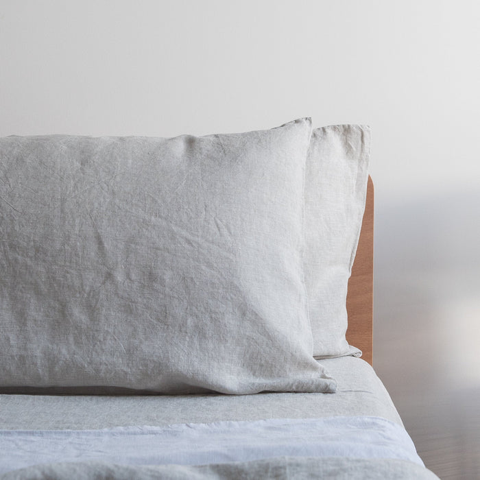 Natural linen pillowcases on a bed with a neutral background