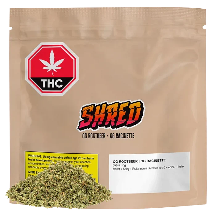 Front view of a tan resealable pouch labeled "OG Rootbeer" with a colorful SHRED logo, THC warning icon, and a small pile of loose dried herb at the base.