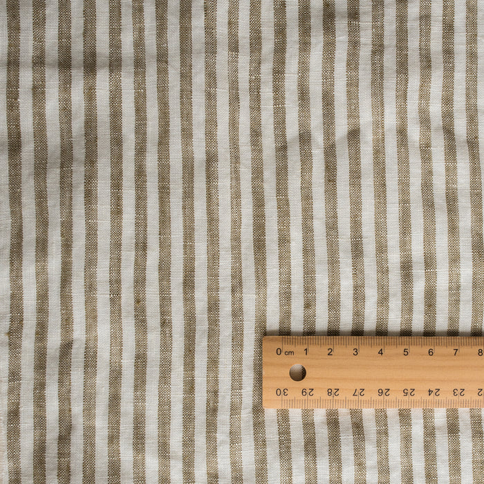 Olive Stripe 100% Linen Fabric with 0.5cm yarn-dyed stripes in olive green and off-white – extra wide, European Flax™ certified with a wooden ruler for scale